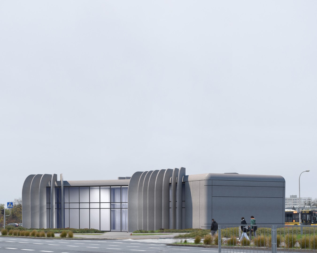 Nowoczesny budynek dworca autobusowego o unikalnej, futurystycznej formie. Elewacja wyróżnia się łukowatymi elementami i szarym wykończeniem. Przeszklone wejście zapewnia naturalne światło, a otoczenie zdobią trawniki i roślinność. W tle widać elementy miejskiej infrastruktury.