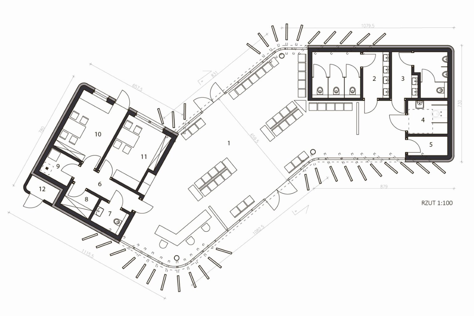 Rzut budynku dworca autobusowego w skali 1:100. Widoczne są pomieszczenia funkcjonalne, takie jak toalety, biura, przestrzeń wspólna i pomieszczenia techniczne. Plan podkreśla nietypowy kształt obiektu, uwzględniając rozmieszczenie drzwi, ścian oraz mebli.